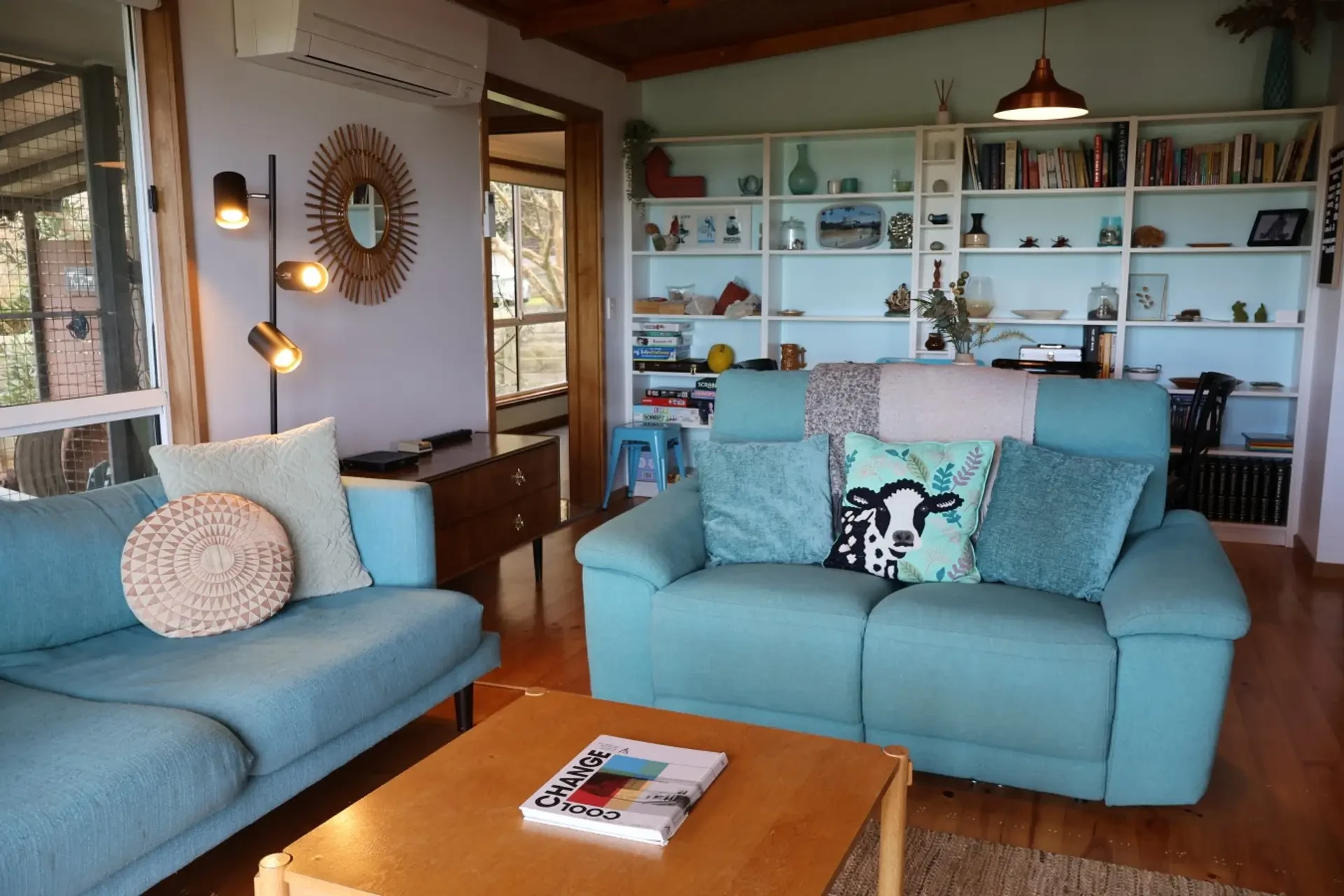 Far View living room with turquoise sofas, timber ceiling and bookshelves