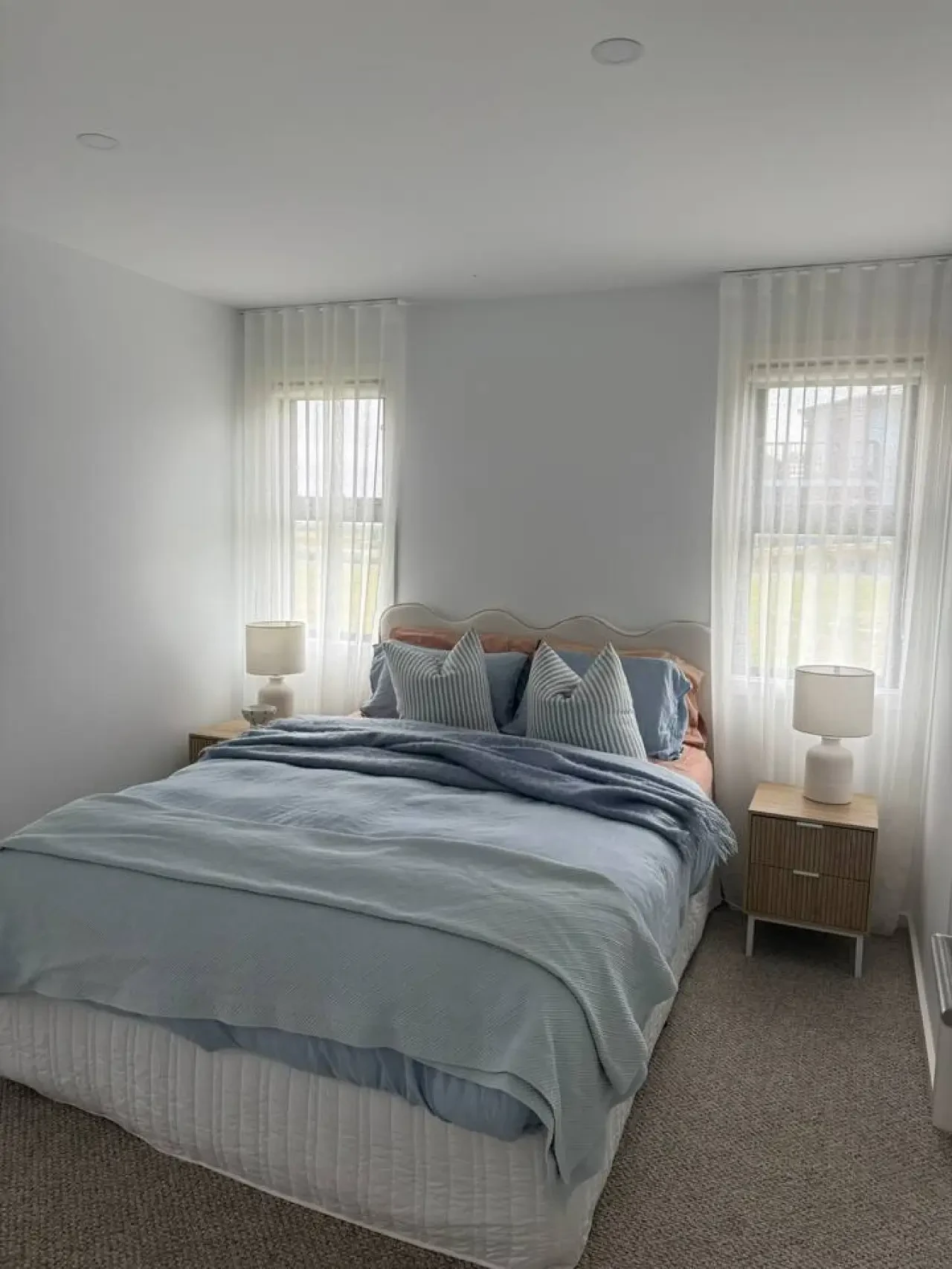Lancaster Lodge master bedroom with blue linen, scalloped headboard and sheer curtains