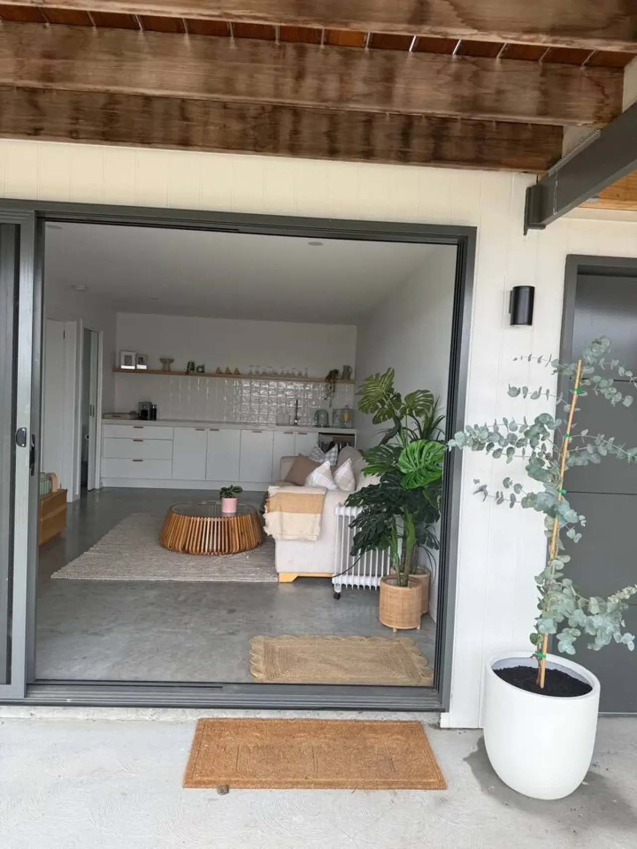 Lancaster Lodge open plan living and kitchen viewed through sliding glass doors with plants