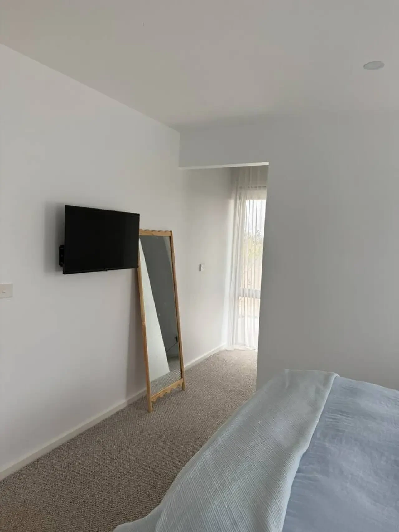 Lancaster Lodge bedroom with wall-mounted TV, floor mirror and sheer curtains