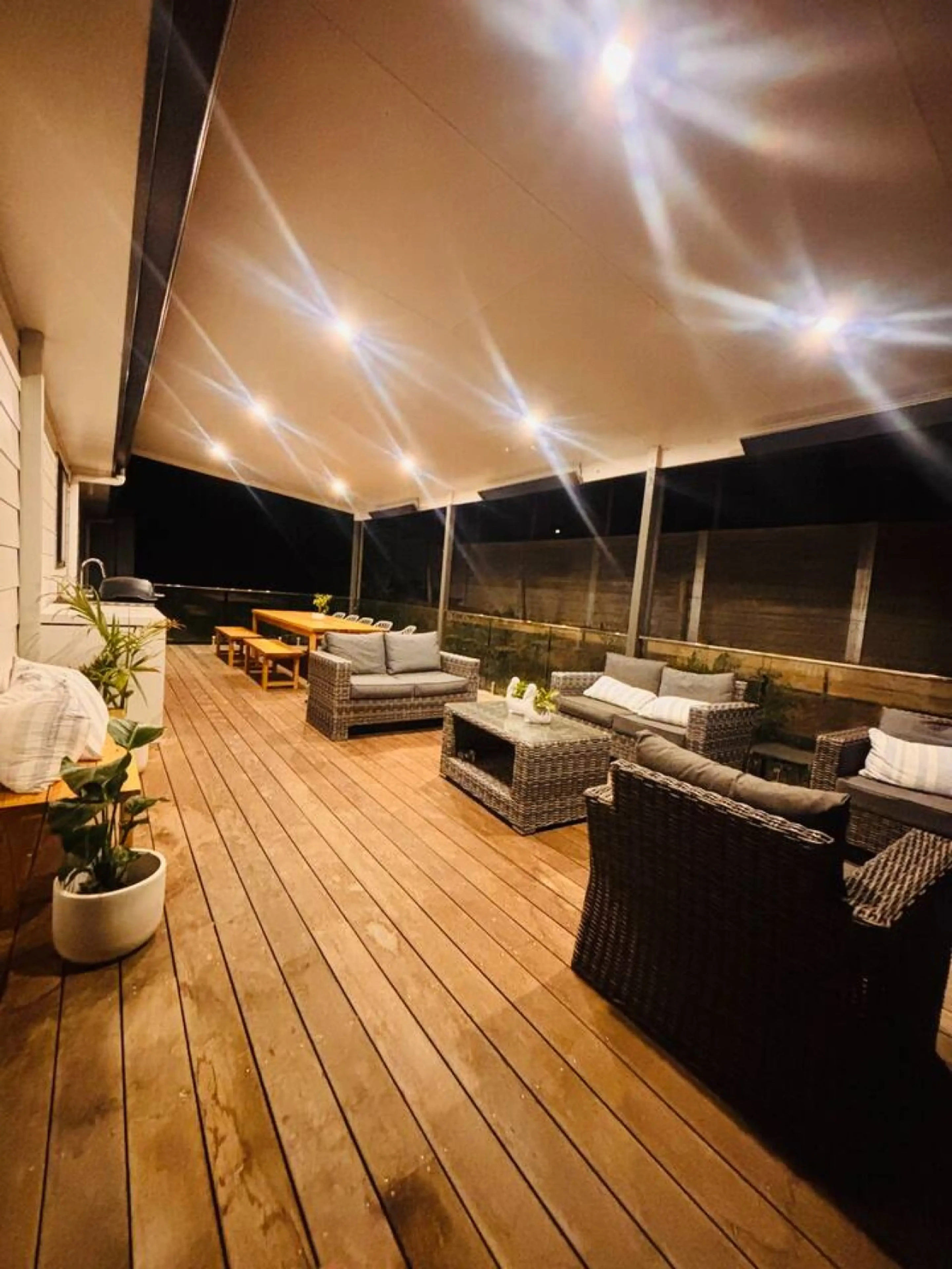 Lancaster Lodge illuminated covered deck at night with wicker lounge furniture