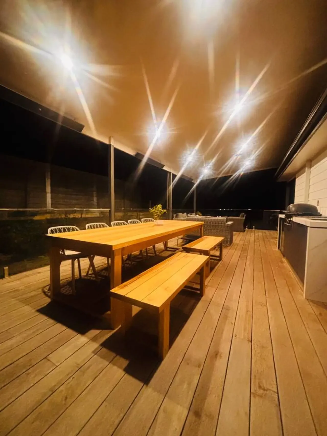 Lancaster Lodge deck at night with long timber table and bench seats