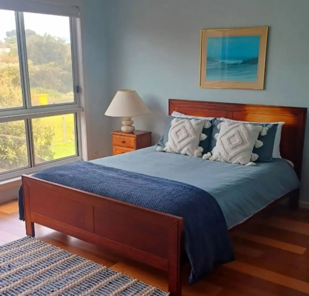 Ocean Blue — master bedroom with ocean artwork and garden view