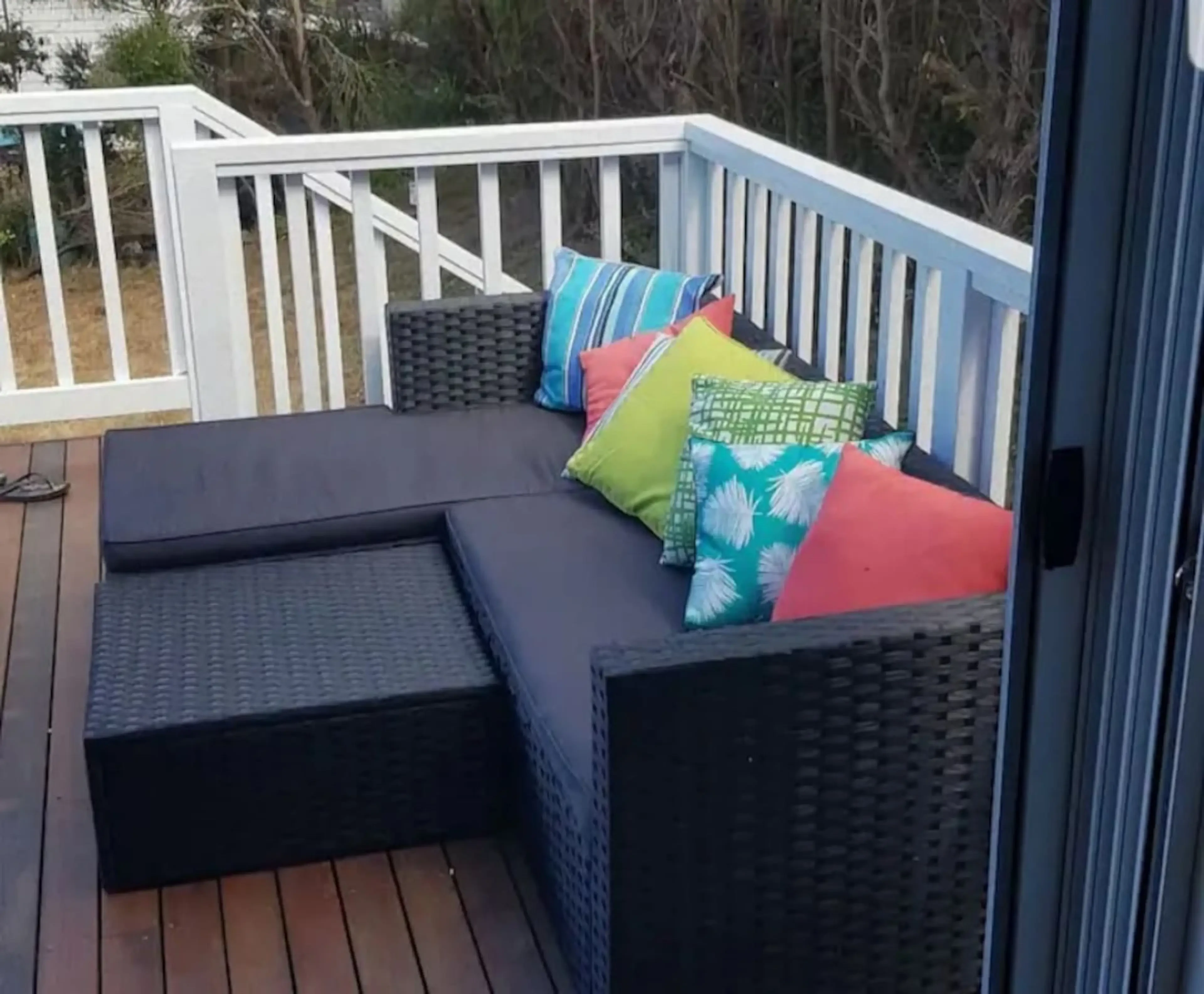 Ocean Blue — deck with black wicker lounge and colourful cushions
