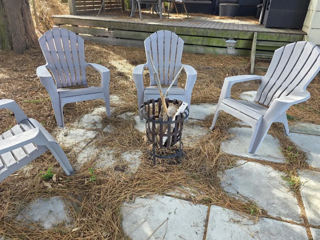 Fire pit area with Adirondack chairs under pine trees