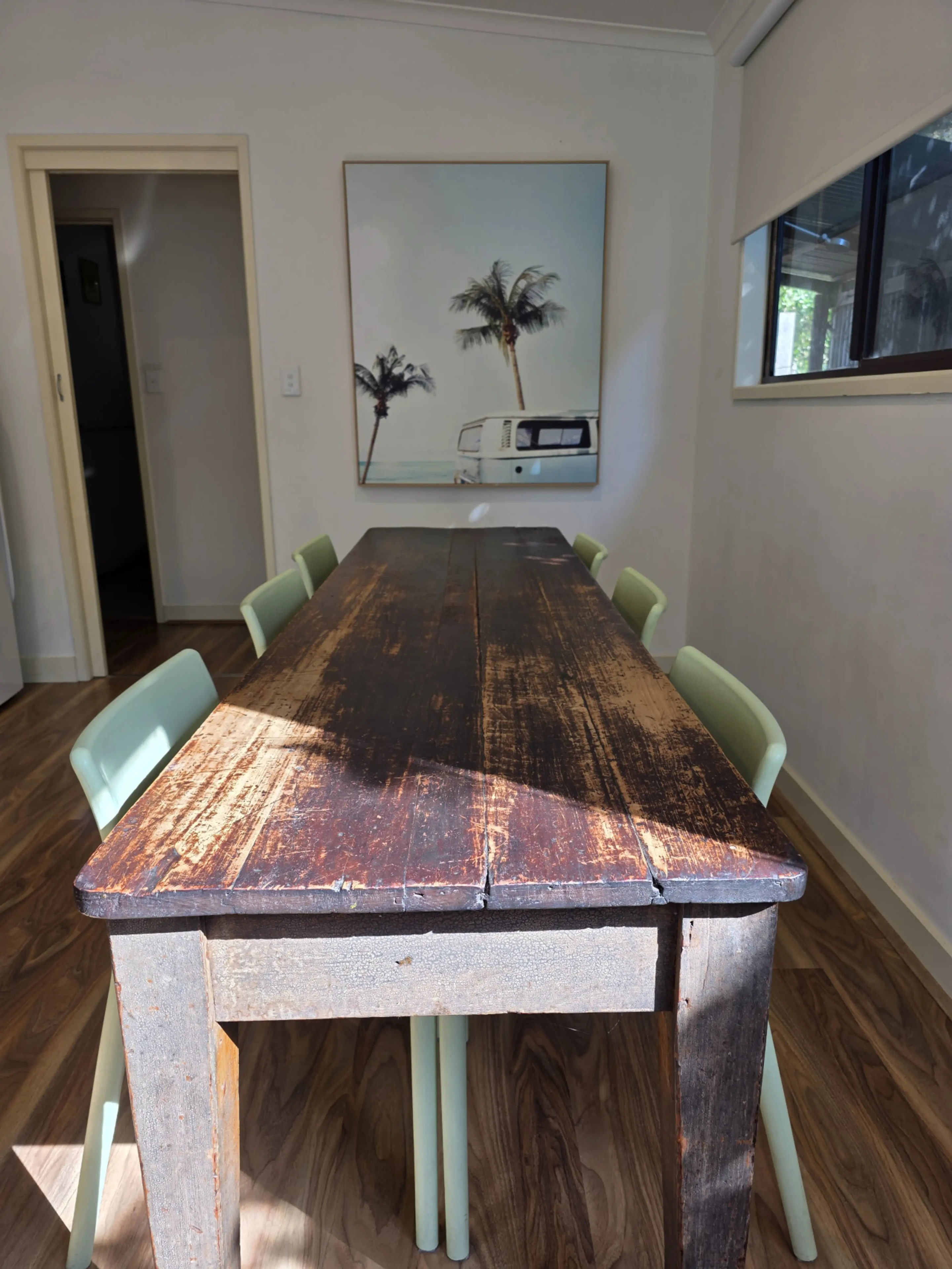 Dining room with rustic timber table and palm tree artwork