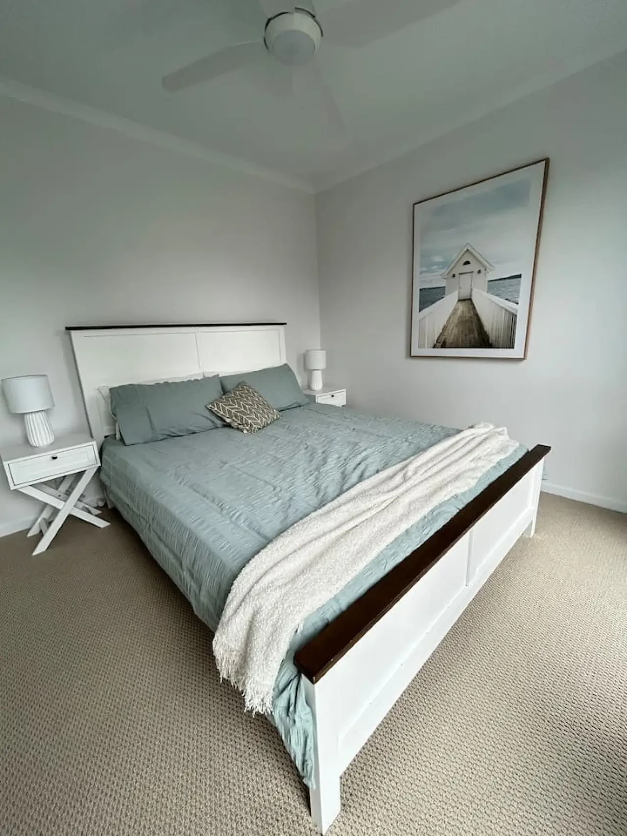 Roo Views bedroom with white timber bed and coastal artwork