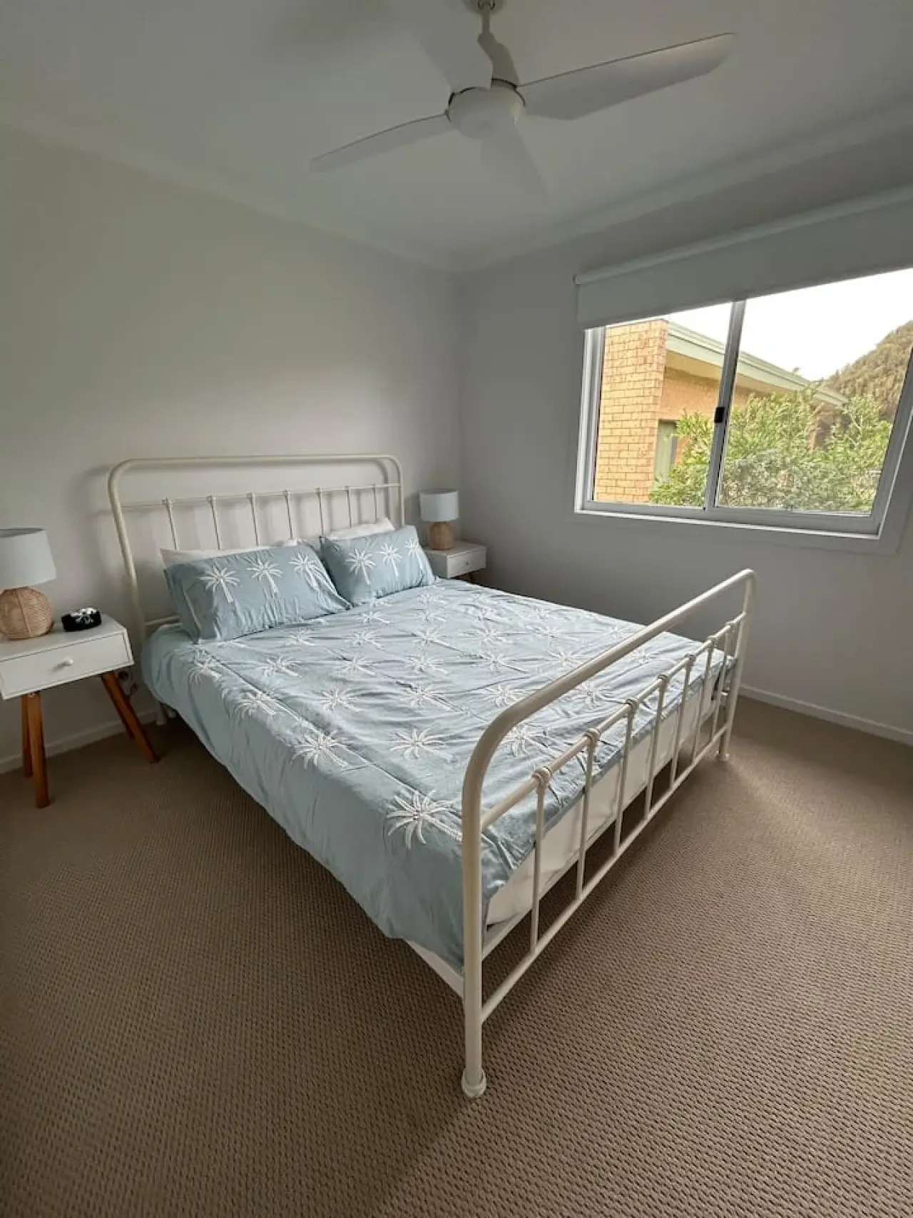 Roo Views bedroom with white iron bed and palm print bedding