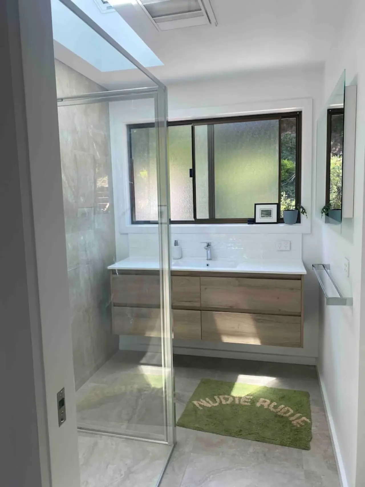 Modern bathroom with skylight, wood vanity and glass shower
