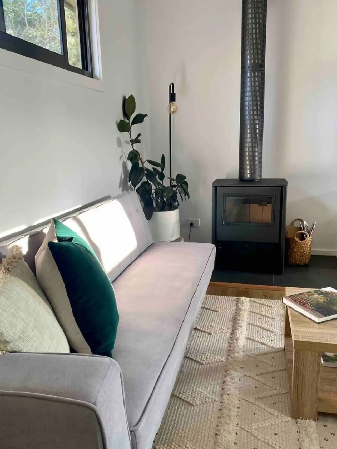 Lounge with wood fire, grey sofa and indoor plants